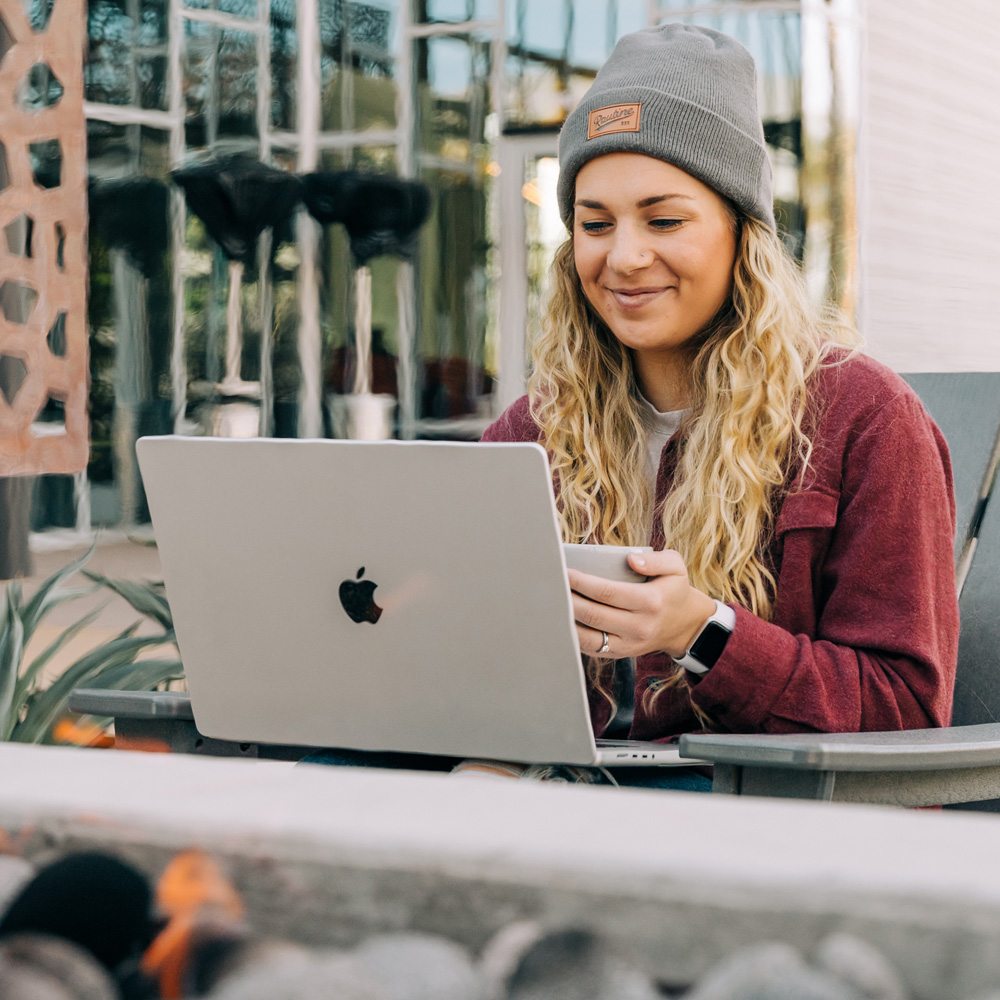 Smiling girl looking at computer holding coffee