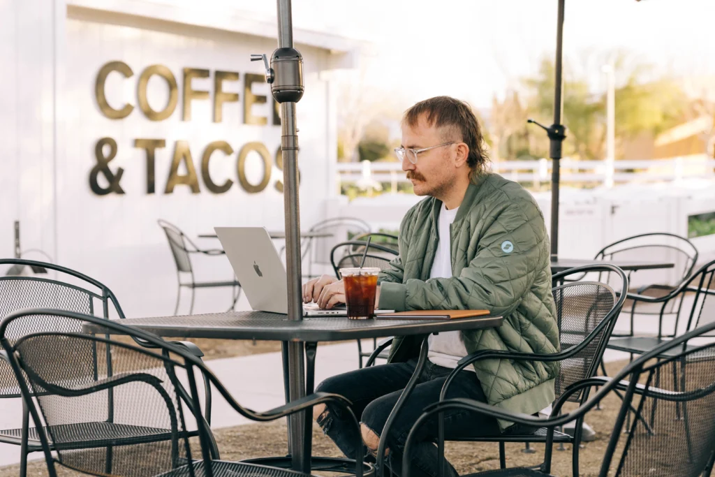 Man sitting at coffee shop with laptop working on conversion rate optimization strategies