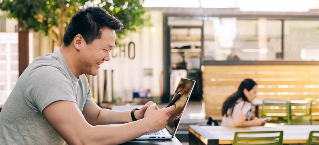 Man looking at phone and computer searching for web design trends of 2025