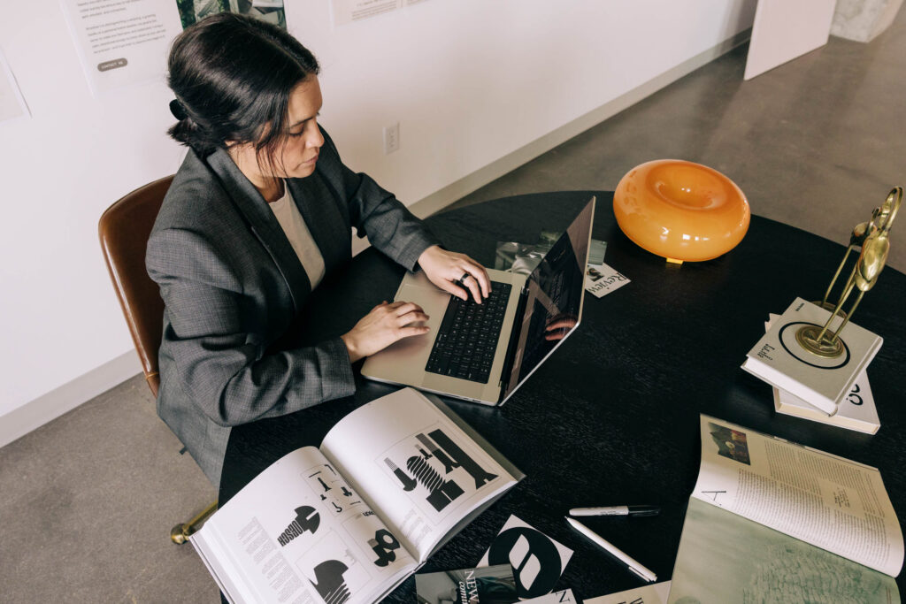 Woman working on a laptop at a table in the 2026 Marketing Playbook blog