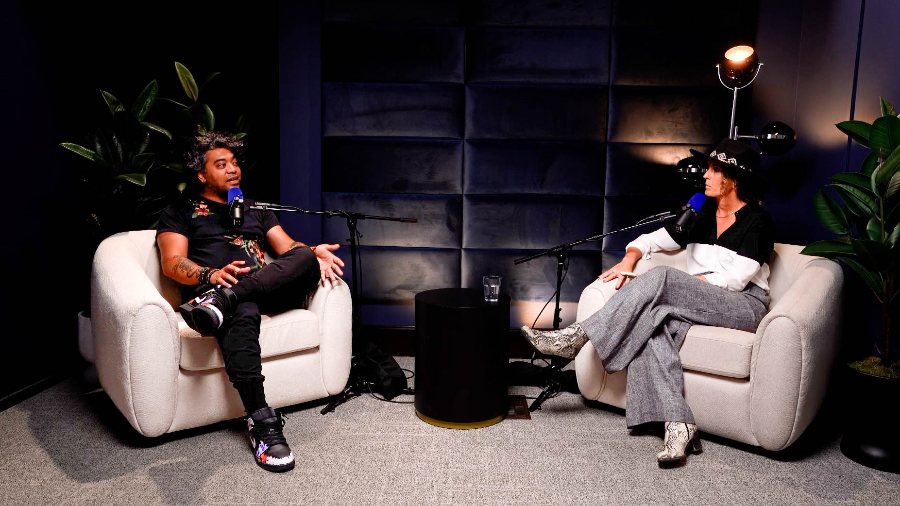 CC Dan Mall Image - Showit Two people sit in armchairs facing each other on a podcast set with microphones and a small round table between them.