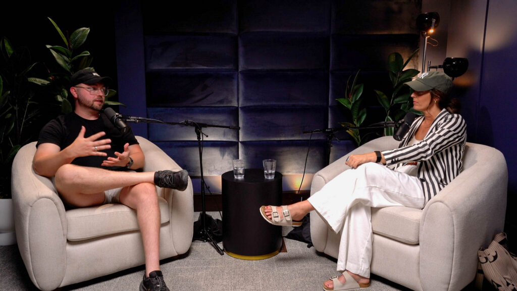Gannon Meyer Image - Showit Two people having a podcast interview in a cozy studio with two microphones and a black padded wall behind them discussing how to turn followers into customers.