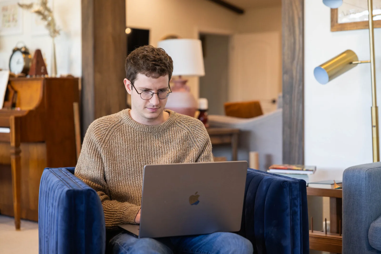 Creative entrepreneur working on a laptop in a navy armchair at home, the kind of small business owner Showit is built for